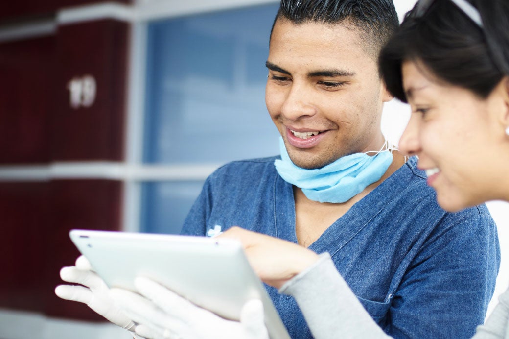 Male and female healthcare workers reviewing data on PC tablet