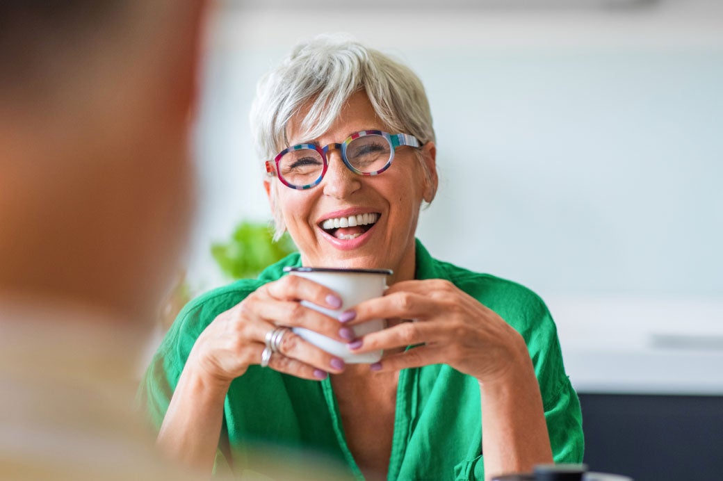 Laughing older woman holding a cup