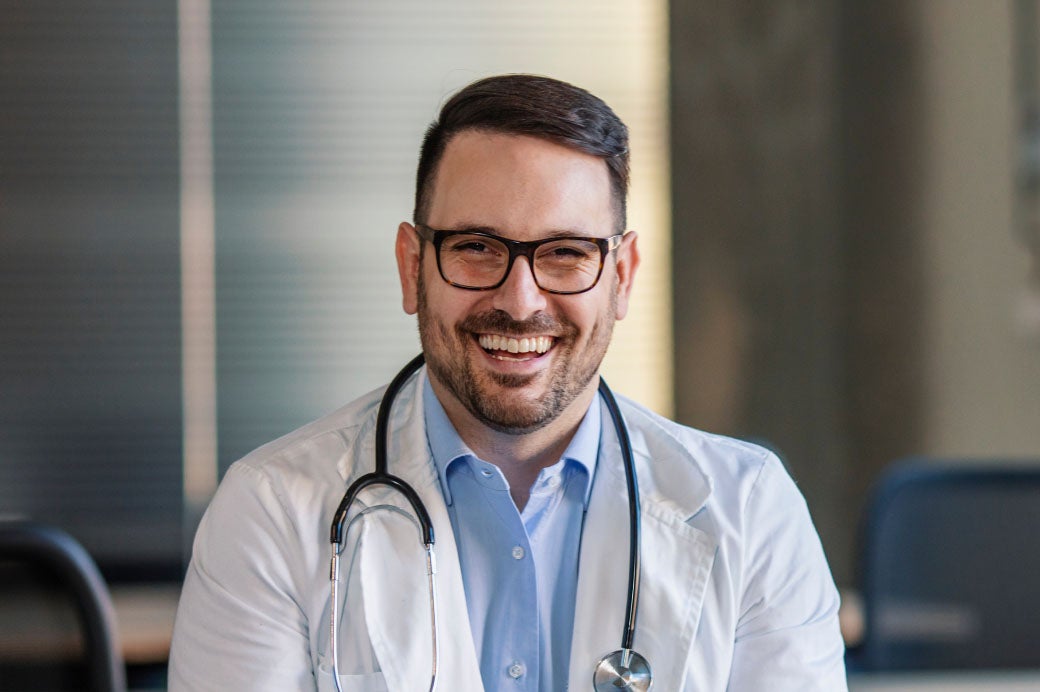 Headshot of smiling healthcare worker with stethoscope around his neck