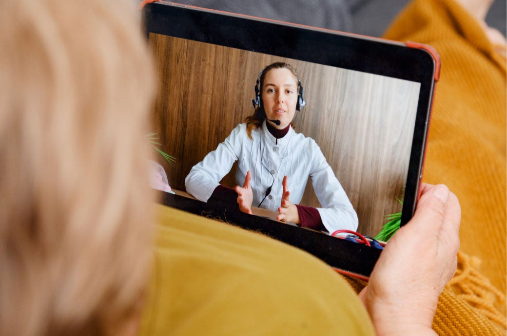 Healthcare consultant wearing headset speaking with a woman via ipad