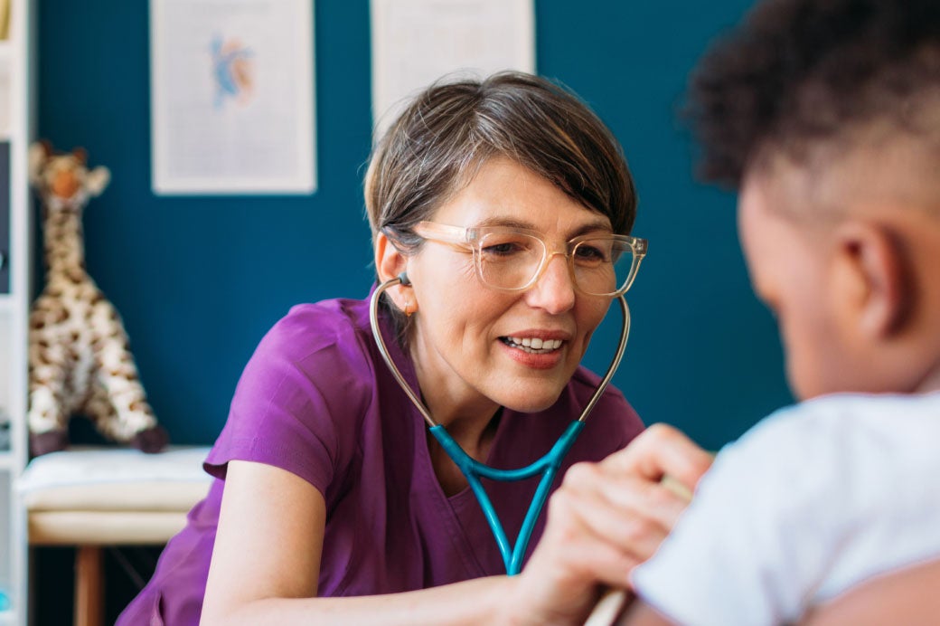 Healthcare worker using a stethoscope to examine a patient.