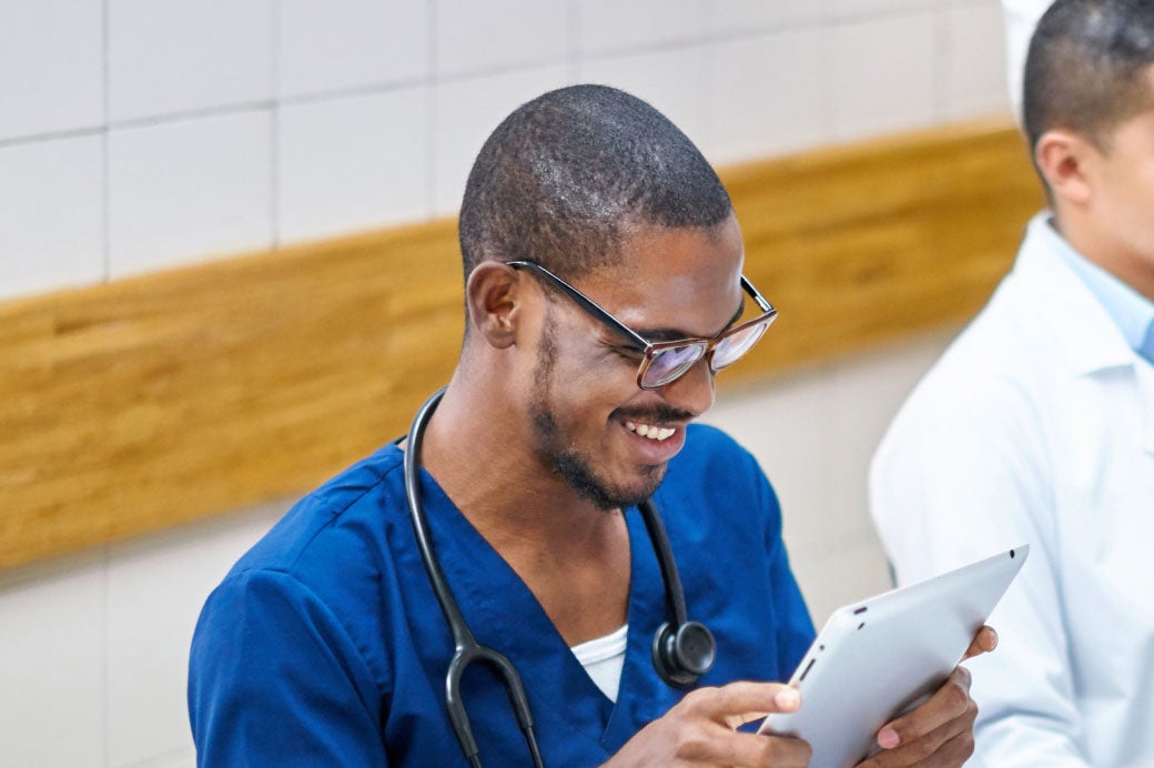 Healthcare worker reviewing records on an iPad.