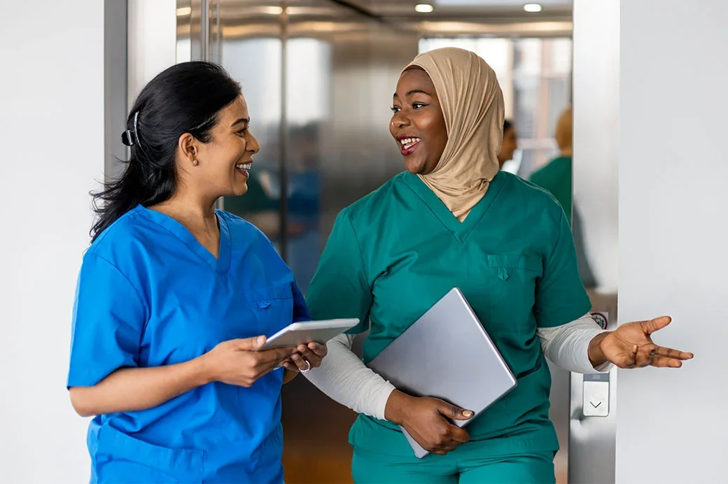Two female nurse healthcare workers discussing
