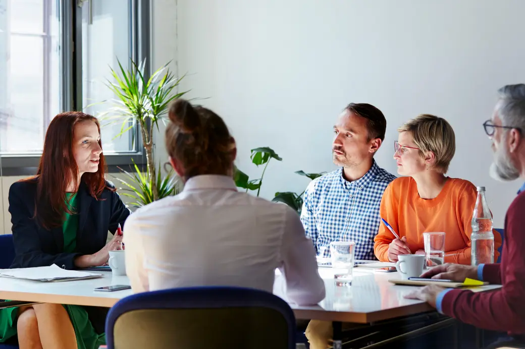 Group of five people meeting around a table.