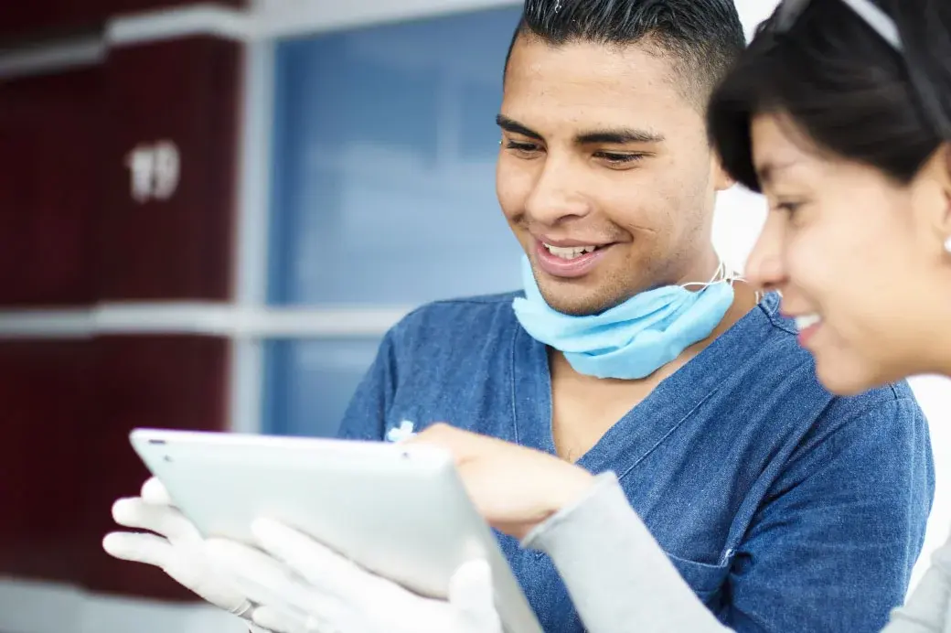 Male and female healthcare workers reviewing data on PC tablet