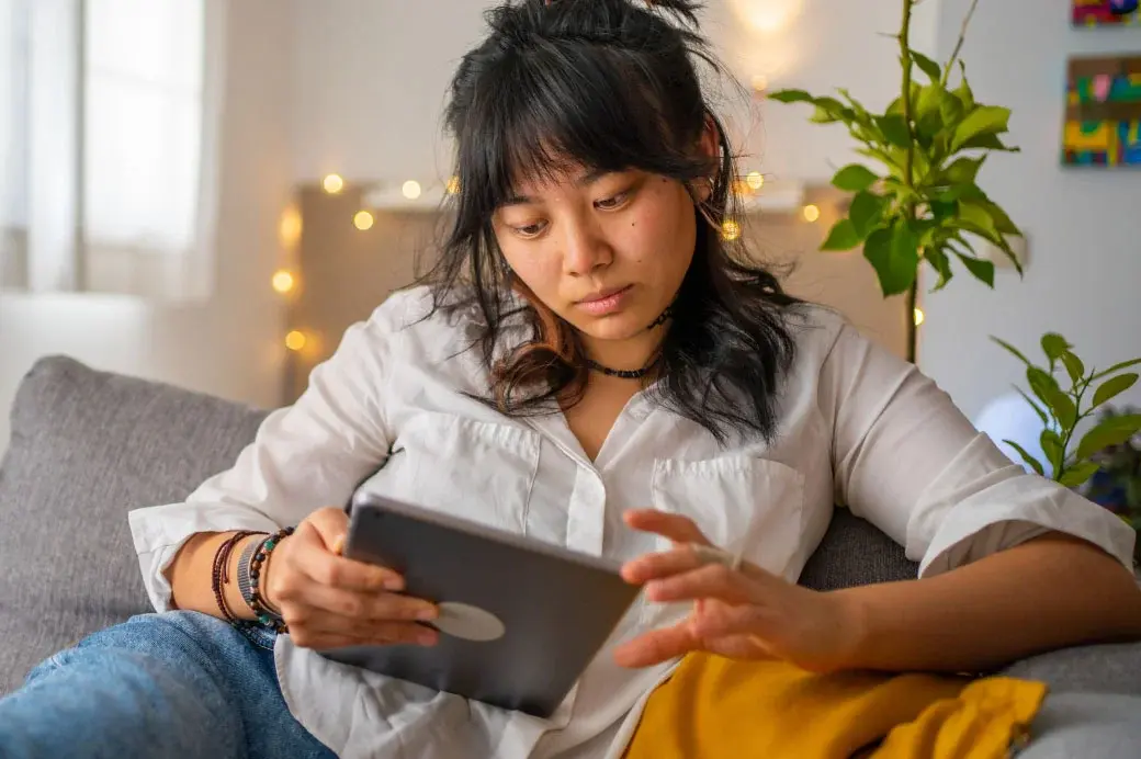/Woman lounging on a couch working on her iPad