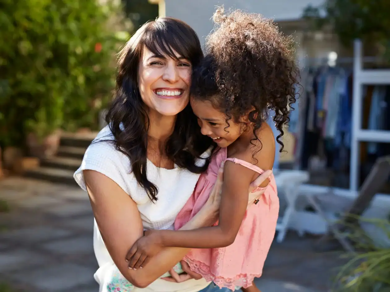 Smiling woman holding and hugging her small child.
