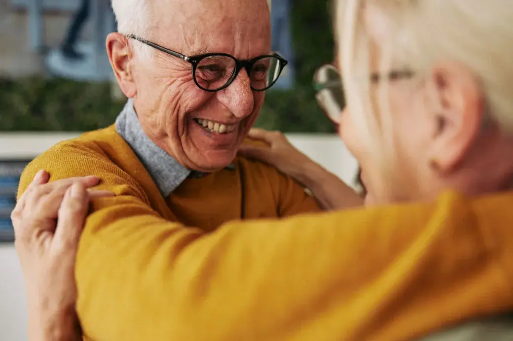 Smiling elderly man hugging a woman.
