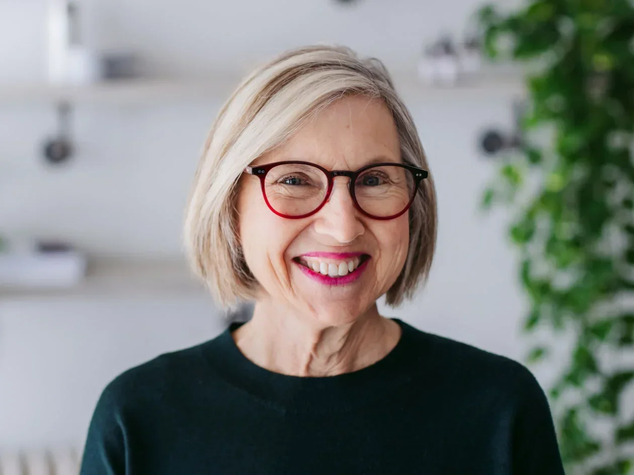 headshot of a smiling older woman with glasses